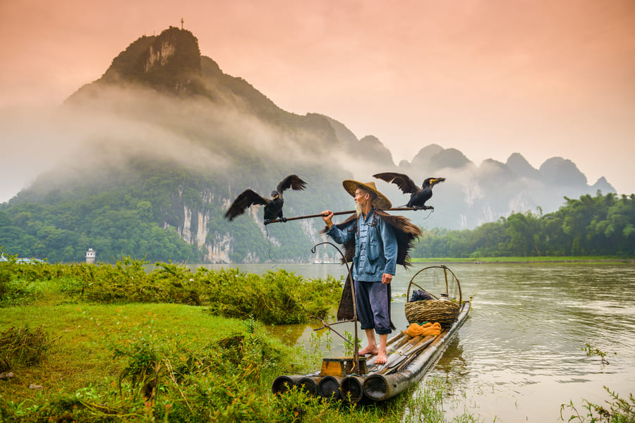 Señor pescando sobre un lago. Detras vista a las montañas de Yangshuo
